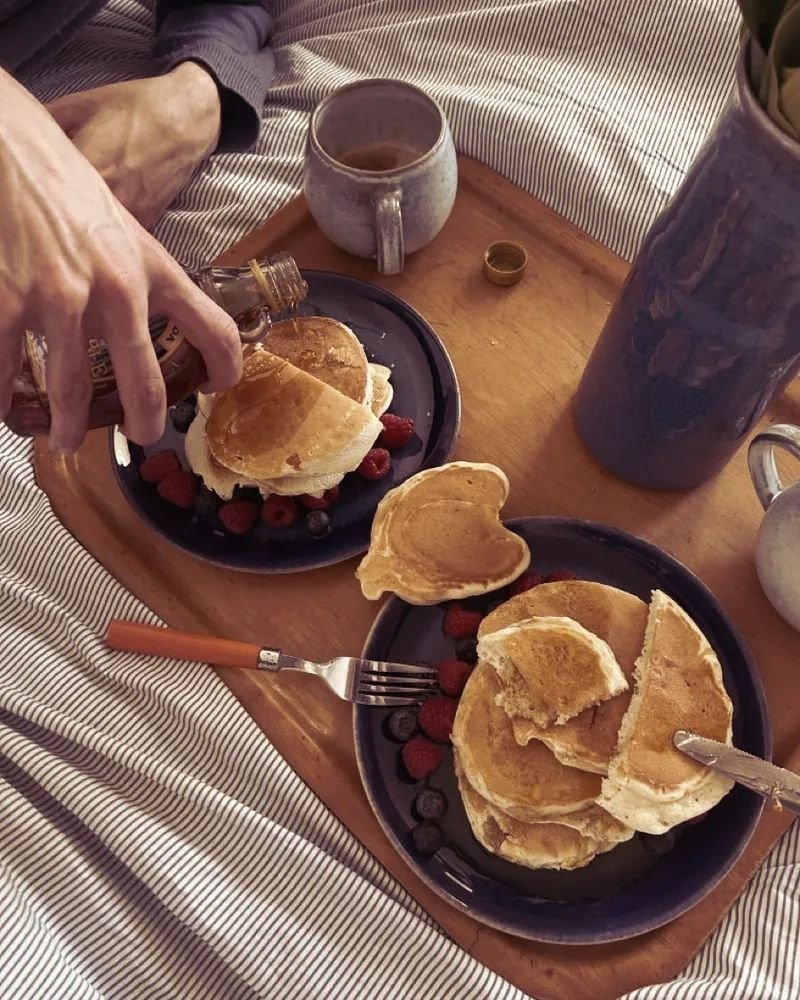 Bandeja con panqueques, frutos rojos y café sobre la cama