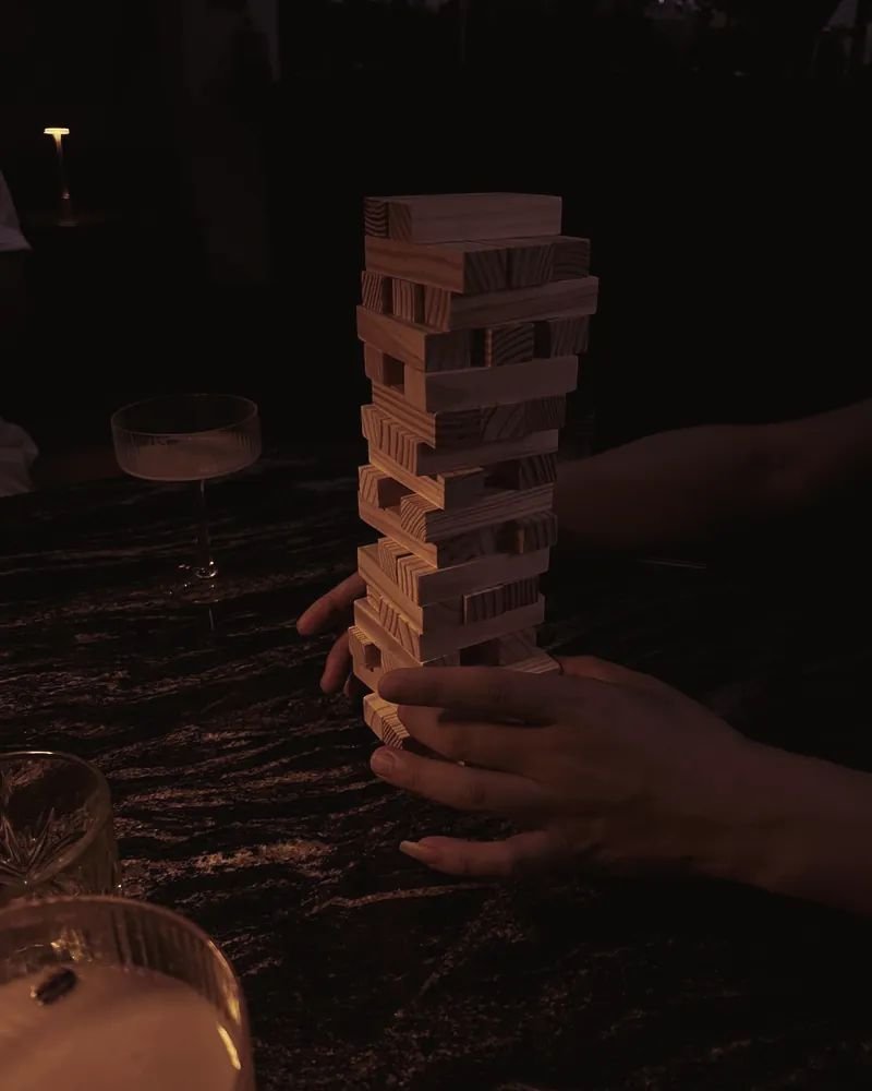 Torre de Jenga en una mesa a media luz, entre copas
